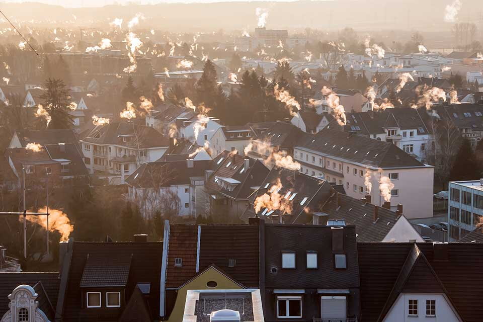 Ausblick auf die Dächer einer Stadt mit rauchenden Schornsteinen