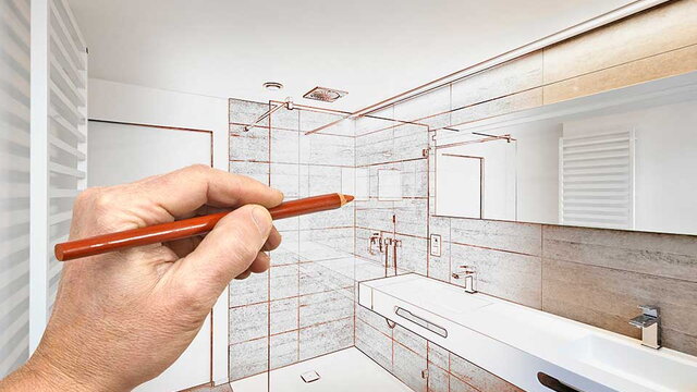 Das Bild zeigt die Hand einer Person, die mit einem roten Stift auf ein modernes Badezimmer zeigt, in dem Teile der Einrichtung – wie Dusche, Waschbecken und Armaturen – als technische Zeichnung über das reale Foto gelegt sind. Es symbolisiert die Planung